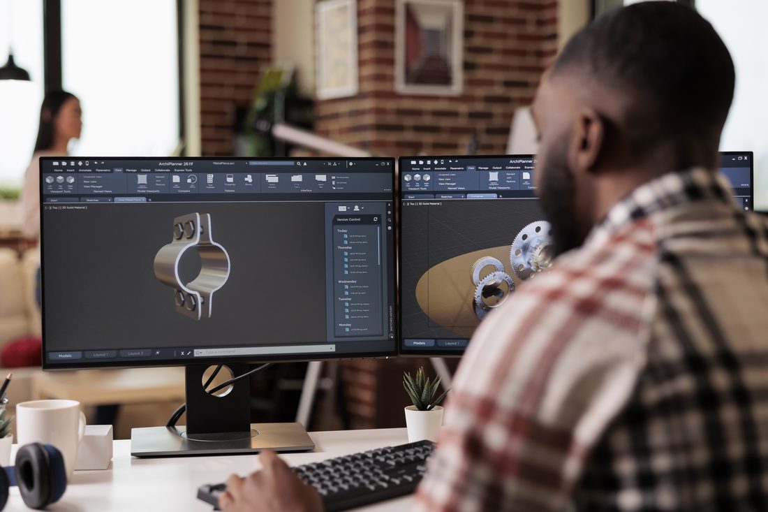 Engineer working on a 3D CAD model across dual monitors